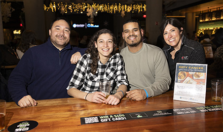 Four attendees enjoy food and drinks at a bar at Time Out Market